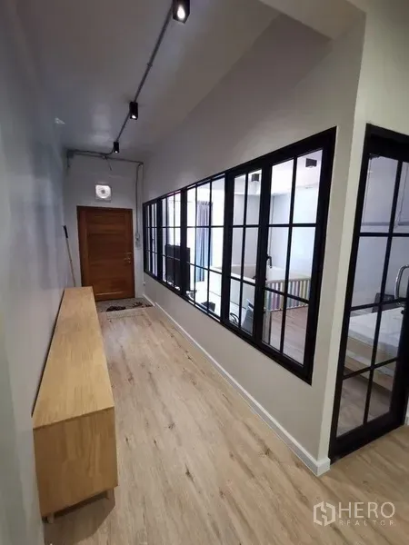 Townhouse for rent in Din Daeng, Bangkok - Bright hallway with black-framed glass partition and light wood flooring in a Huai Khwang townhouse.
