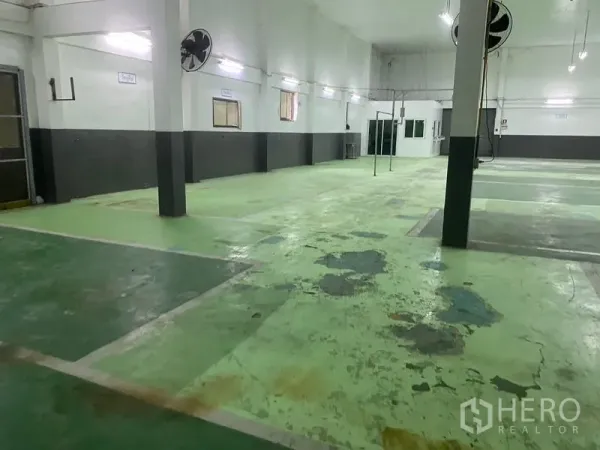 Warehouse for rent in Lam Luk Ka, Pathum Thani - Spacious warehouse interior with high ceiling, fans and marked green epoxy floor