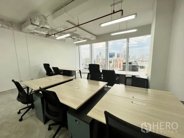 办公空间 出租在Sathon, Bangkok - 靠近全景窗的工位，外露天花与LED长条灯。