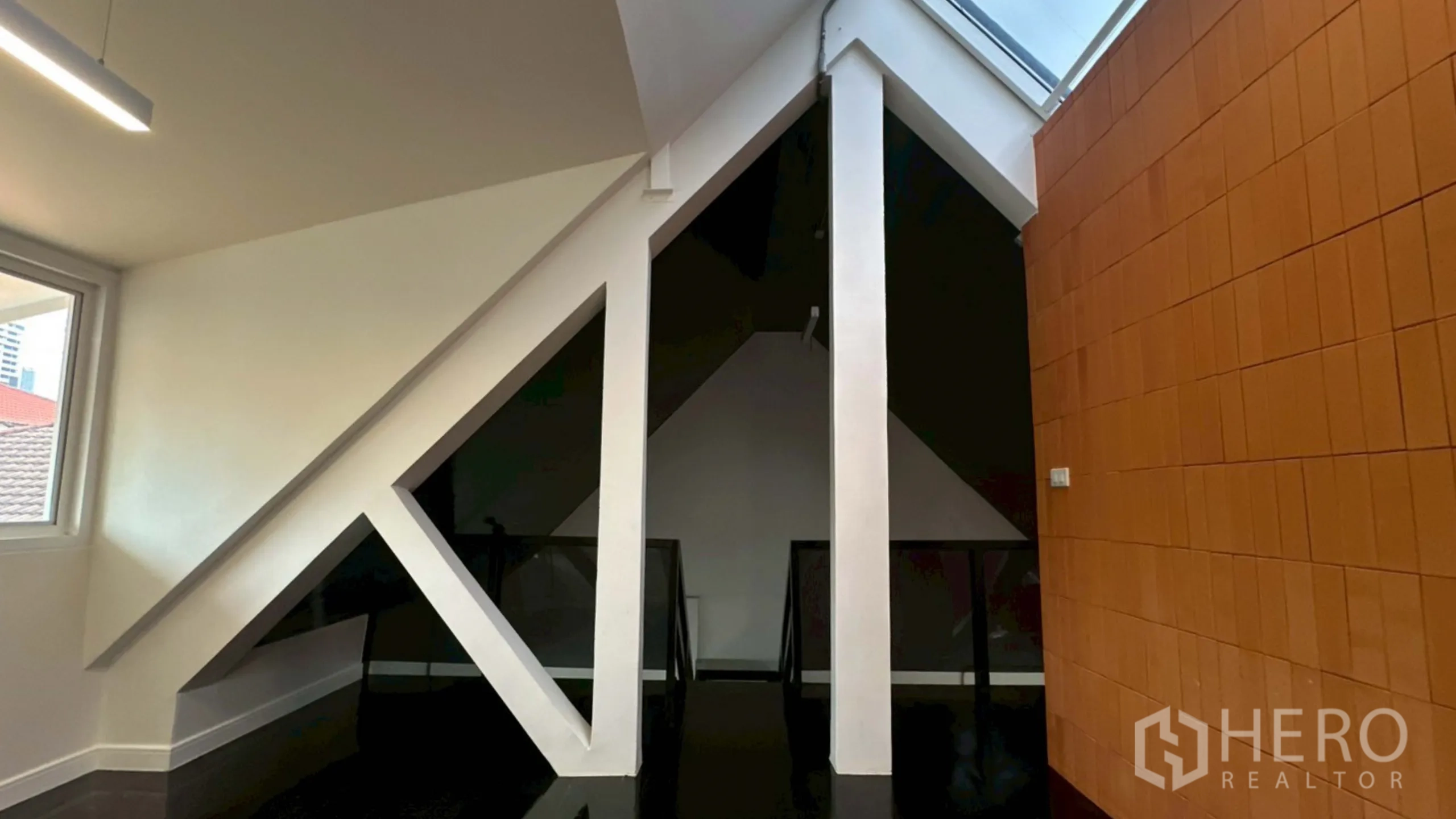 Home Office for rent in Watthana, Bangkok - A-frame structural columns under a skylight beside a terracotta wall.