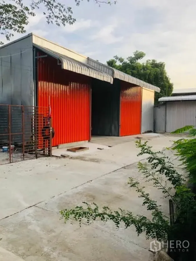Warehouse for rent in Wang Thonglang, Bangkok - Warehouse exterior with bright red sliding steel doors, wide concrete yard and awning roof.