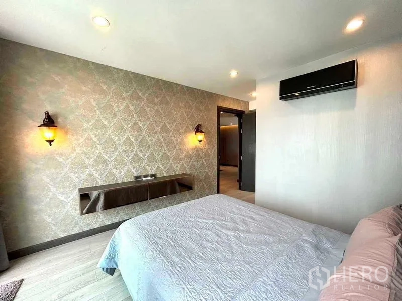公寓 出售在Watthana, Bangkok - 明亮卧室，墙面花纹壁纸、壁灯与舒适大床。