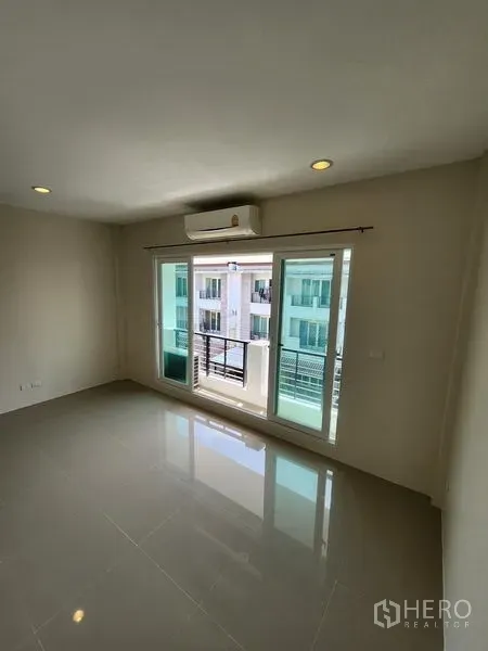 联排别墅 出租在Wang Thonglang, Bangkok - 明亮客厅，亮面地砖，推拉落地门通阳台，配空调。
