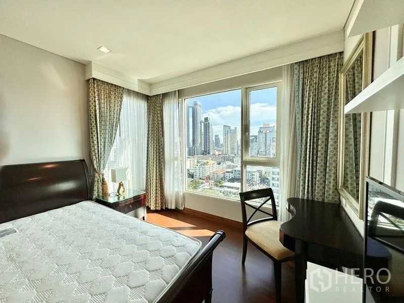 Condominium for rent in Watthana, Bangkok - Corner bedroom with large windows, desk, and Bangkok skyline view.