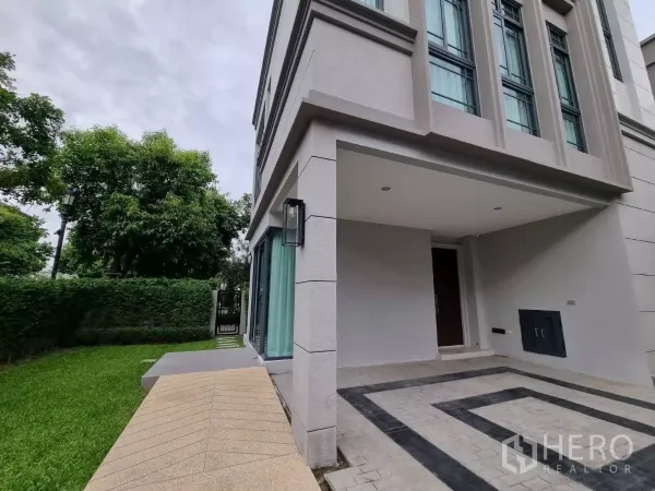 独立式住宅 出售在Prawet, Bangkok - 转角地块的侧院草坪与车道，带侧门与门廊。