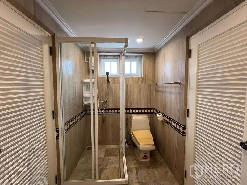 Detached House for rent in Bang Phli, Samut Prakan - Tiled bathroom with glass shower and toilet between louvered doors.