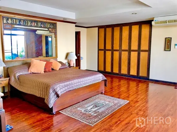 公寓 出租或出售在Watthana, Bangkok - 主卧宽敞，木地板，整面衣柜与大镜面床头，空间明亮舒适。
