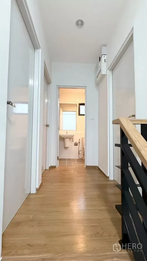 Townhouse for rent in Bang Phli, Samut Prakan - Upstairs corridor with wood flooring leading to bathrooms and bedrooms.