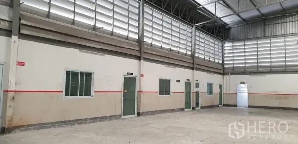 Warehouse for rent in Lam Luk Ka, Pathum Thani - Interior wall lined with multiple doors and windows below louvered ventilation panels.