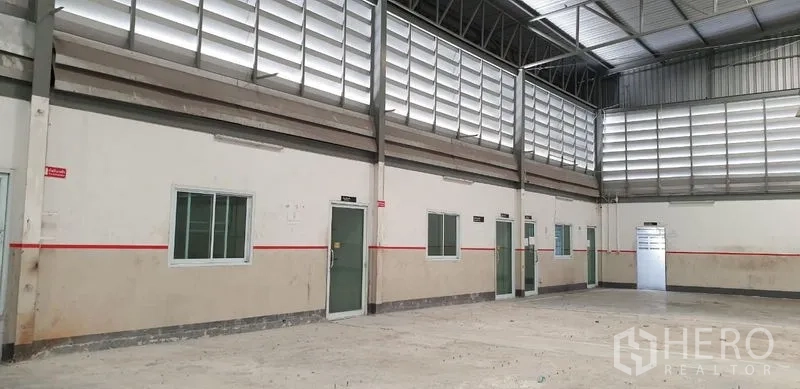 Warehouse for rent in Lam Luk Ka, Pathum Thani - Interior wall lined with multiple doors and windows below louvered ventilation panels.