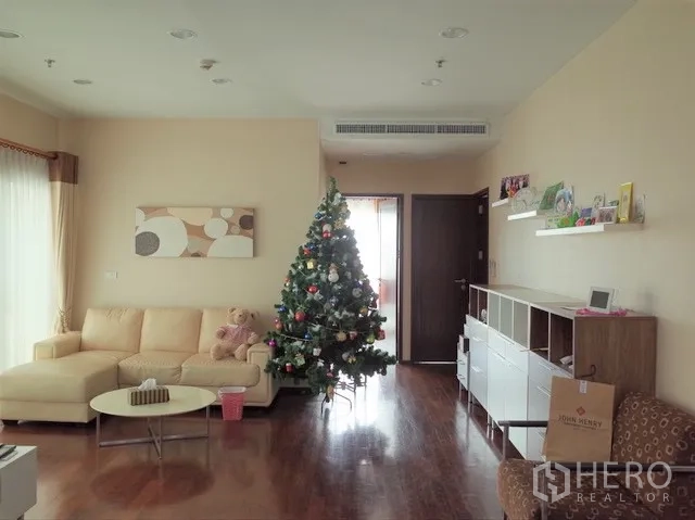 公寓 出售在Watthana, Bangkok - 明亮客厅，木地板、转角沙发与圣诞树，通透采光的通罗公寓