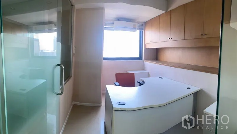 Office Space for rent in Din Daeng, Bangkok - Executive corner room with overhead cabinets, desk and natural light from the window.