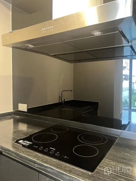 公寓 出租在Watthana, Bangkok - 现代厨房一角，电磁炉与不锈钢抽油烟机、镜面挡板