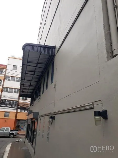 Townhouse for sale in Bang Kapi, Bangkok - Side exterior of the townhouse with long awning and narrow lane access.