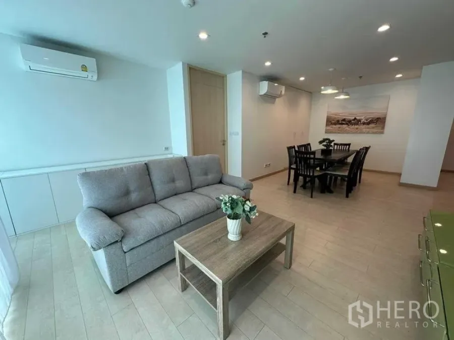 公寓 出售在Bang Rak, Bangkok - 温馨客厅，灰色沙发、茶几与临近的用餐区。