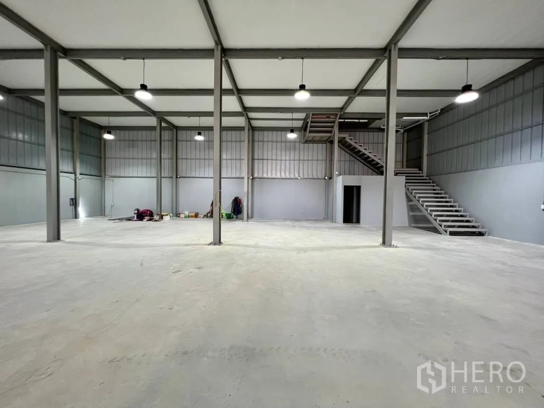 Warehouse for rent in Sai Mai, Bangkok - Spacious warehouse interior with steel columns, concrete floor and side staircase to mezzanine.