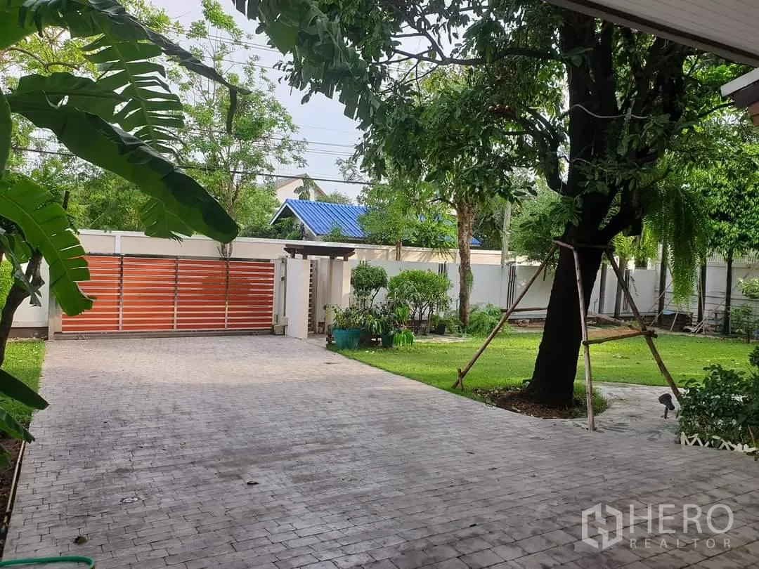 独立式住宅 出租在Bang Kapi, Bangkok - 宽阔车道通向滑动大门，周围绿树成荫。