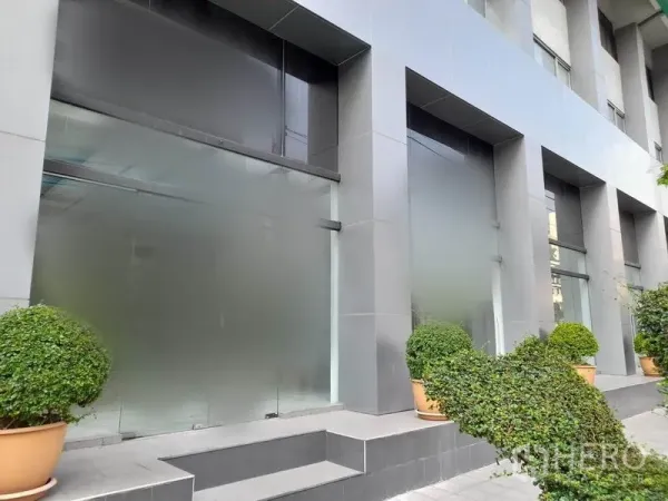 零售空间 出租在Ratchathewi, Bangkok - 拉差贴威现代商铺外立面，大面积磨砂玻璃、灰色立柱与绿植花盆。