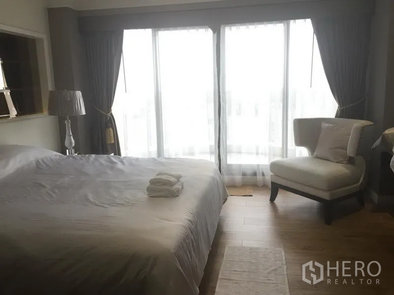 公寓 出租在Bang Rak, Bangkok - 采光充足的卧室，配大床与单人沙发，落地窗搭配窗帘。