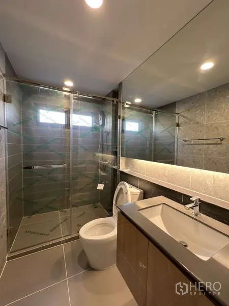 Detached House for rent in Bang Kapi, Bangkok - Contemporary bathroom with wide mirror, floating vanity and glass shower.