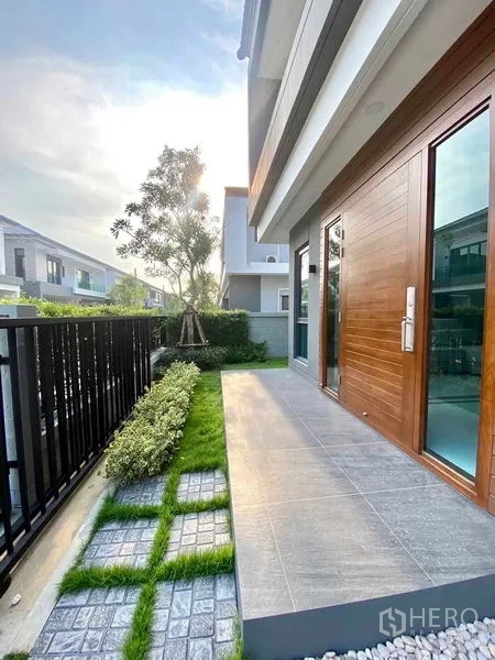 独立式住宅 出租或出售在Bang Phli, Samut Prakan - 前庭露台，瓷砖地面、木质入户门、绿篱与金属栏杆。