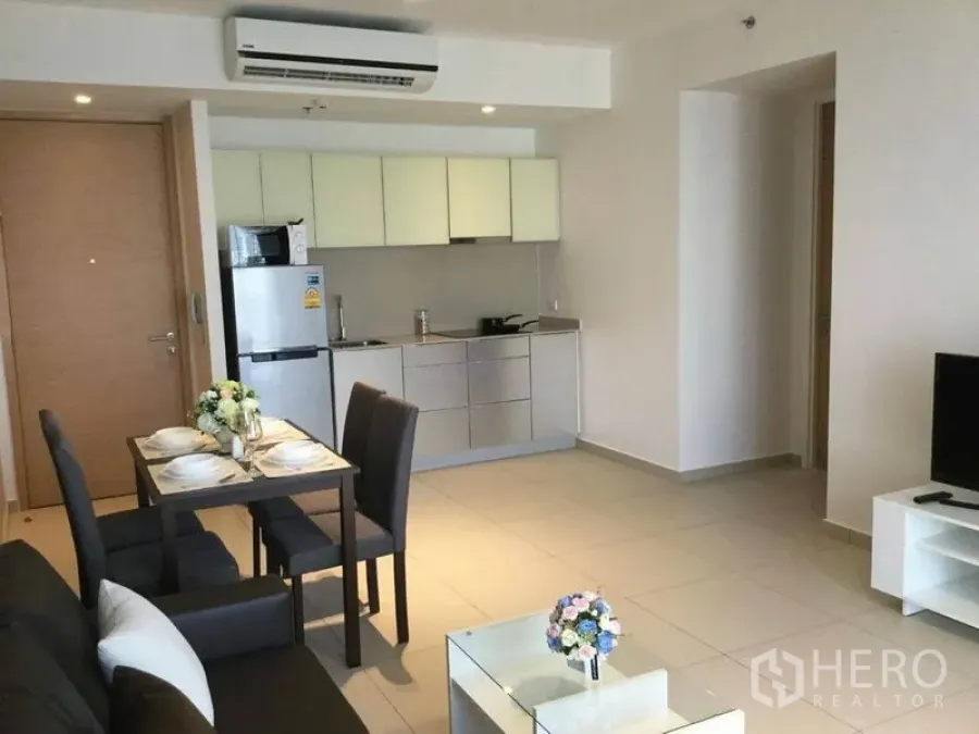 公寓 出租在Watthana, Bangkok - 开放式客厅与一体化厨房，四人餐桌与冰箱。