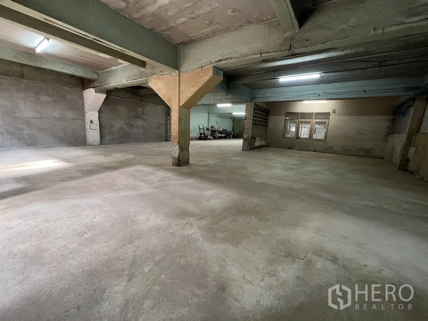 Warehouse for rent in Phra Pradaeng, Samut Prakan - Open-plan warehouse area with concrete floor, support columns, and fluorescent lighting.