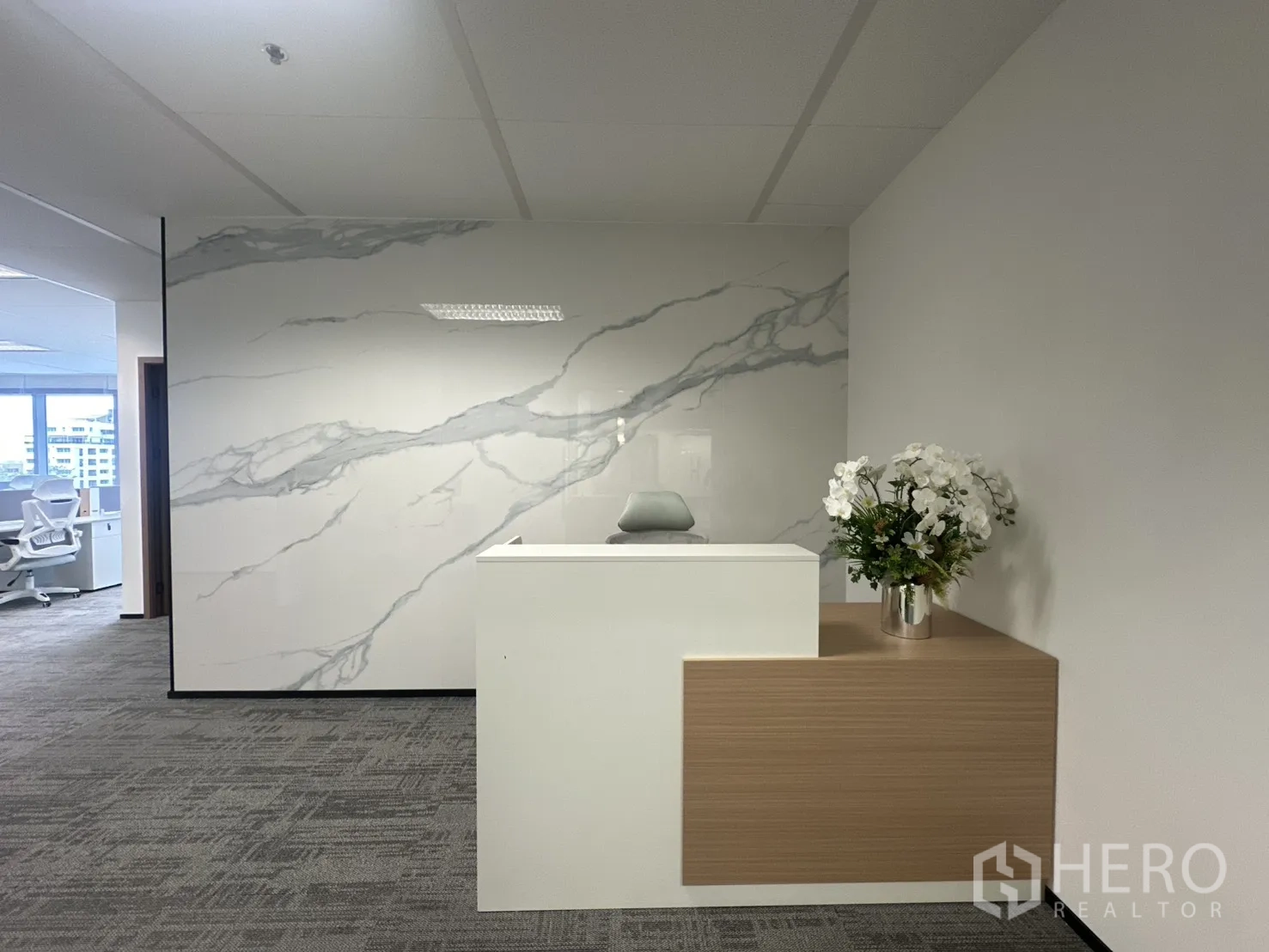 Office Space for rent in Pathum Wan, Bangkok - Reception counter against a marble feature wall with decorative flowers.