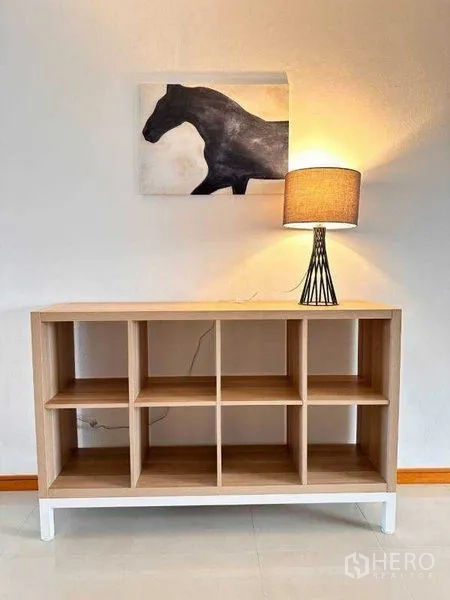 Apartment for rent - Minimal console shelf with a table lamp and horse artwork on a white wall.