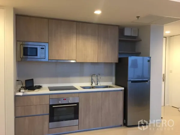 公寓 出租或出售在Ratchathewi, Bangkok - 现代嵌入式厨房，木质柜体、烤箱、灶台与不锈钢冰箱。