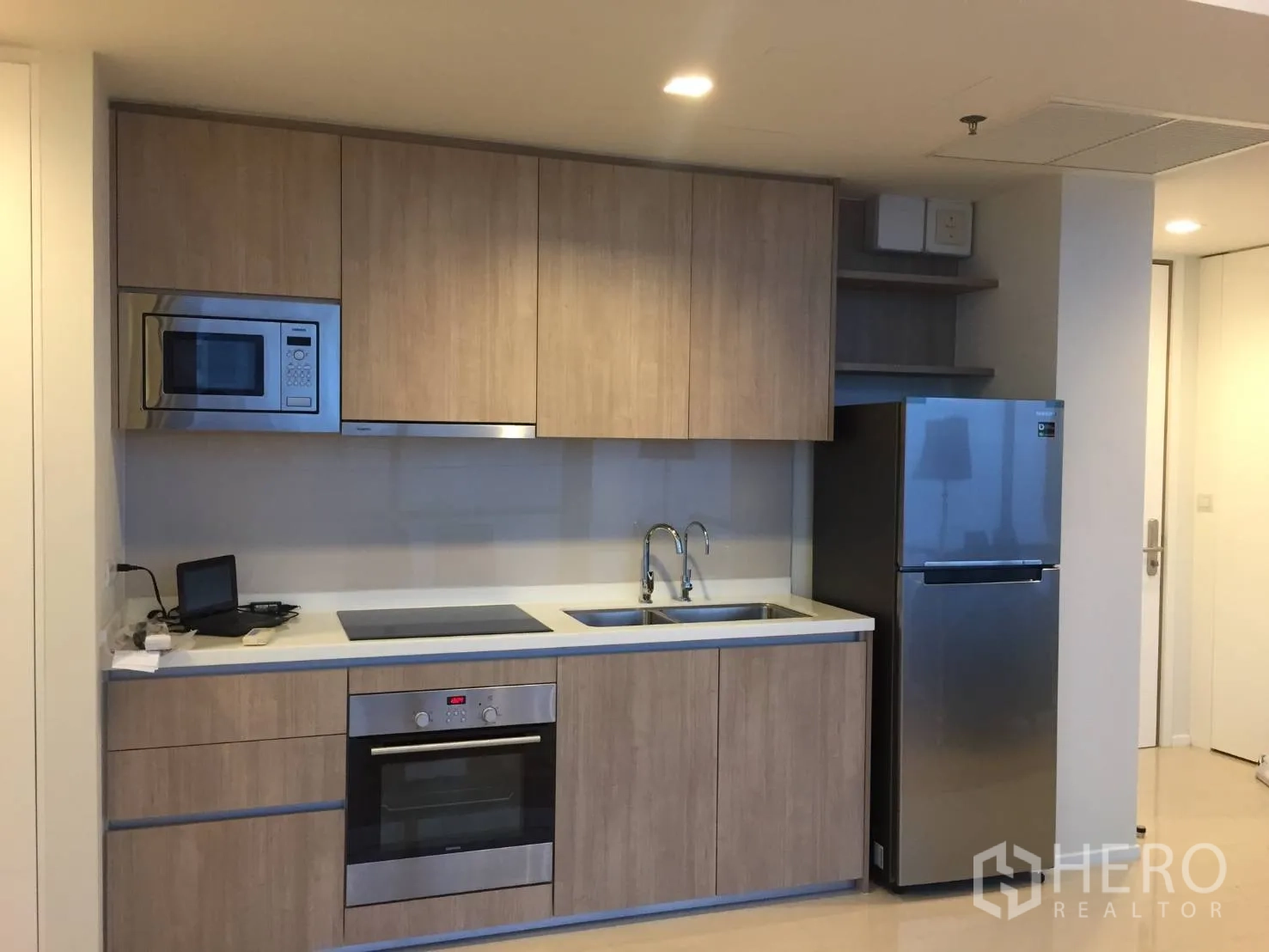 公寓 出租或出售在Ratchathewi, Bangkok - 现代嵌入式厨房，木质柜体、烤箱、灶台与不锈钢冰箱。