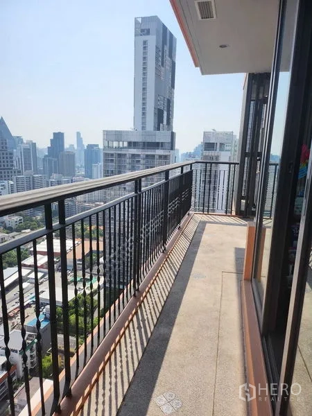 Condominium for sale in Khlong Toei, Bangkok - Narrow balcony corridor along a glass wall facing modern towers.