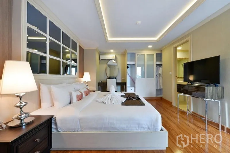 Apartment for rent in Khlong Toei, Bangkok - Bedroom overview with king bed, open wardrobe, bedside tables, and TV console.