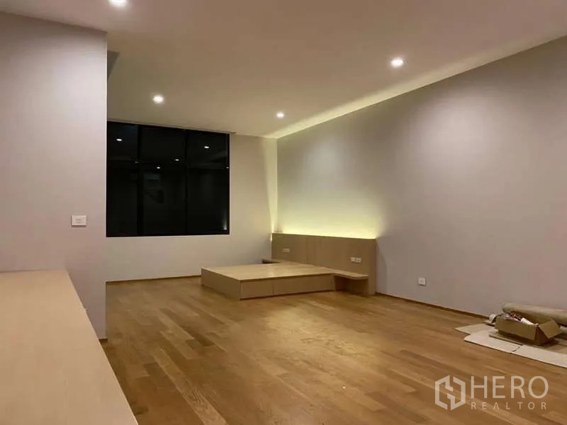 Townhouse for rent or sale in Saphan Sung, Bangkok - Large master suite at night with recessed lights, platform bed and black-framed windows.