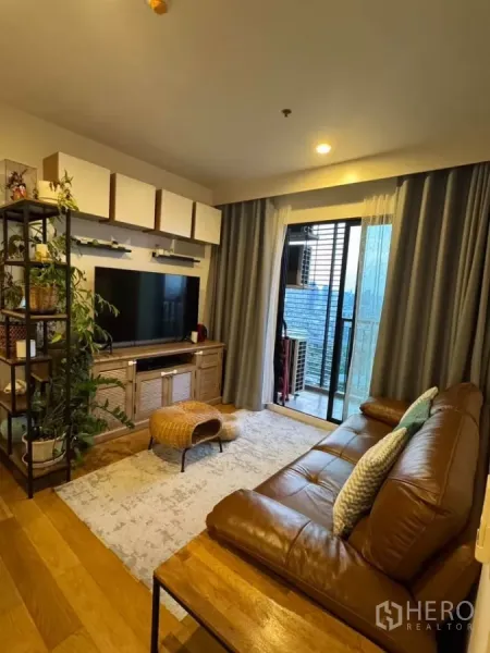 คอนโด ให้เช่าในWatthana, Bangkok - ห้องนั่งเล่นอบอุ่น โซฟาหนัง ทีวี พื้นไม้ และประตูระเบียงวิวเมือง