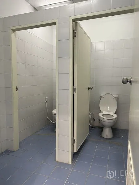 Factory for rent in Khlong Luang, Pathum Thani - Tiled restroom stalls with Western toilets in the industrial facility.