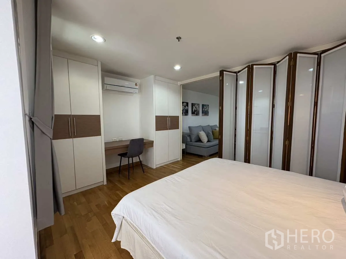 Condominium for rent in Khlong Toei, Bangkok - Bedroom with built‑in wardrobes, study desk and folding partition doors.