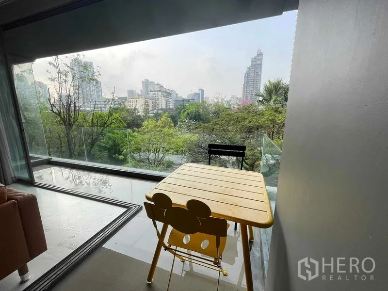 公寓 出租或出售在Watthana, Bangkok - 阳台用餐角，可观城市天际线和树梢景色，近Phrom Phong。