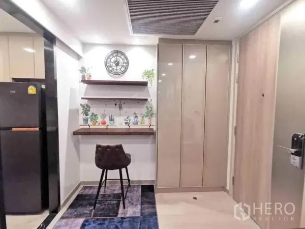 Condominium for rent or sale in Huai Khwang, Bangkok - Compact entry with built-in desk, floating shelves, and wardrobe beside the kitchen fridge.