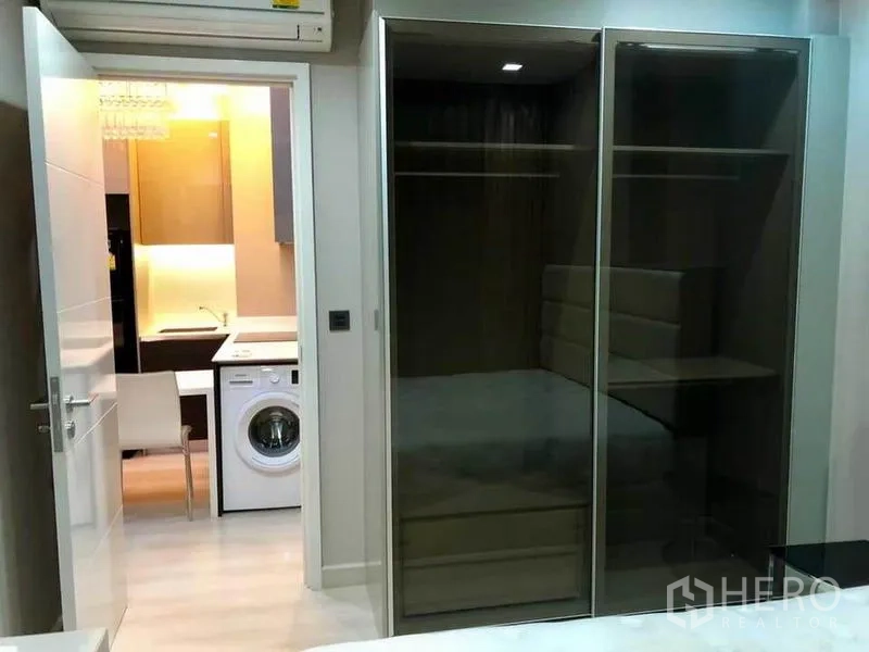 Condominium for rent or sale in Phaya Thai, Bangkok - Bedroom with sliding glass wardrobe facing the kitchen with a washing machine.