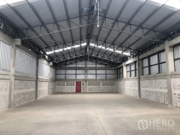 Factory for rent in Khlong Luang, Pathum Thani - Open factory floor with high steel-truss roof, ventilated upper walls and concrete surface.