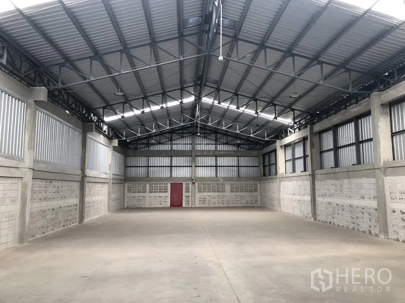 Factory for rent in Khlong Luang, Pathum Thani - Open factory floor with high steel-truss roof, ventilated upper walls and concrete surface.