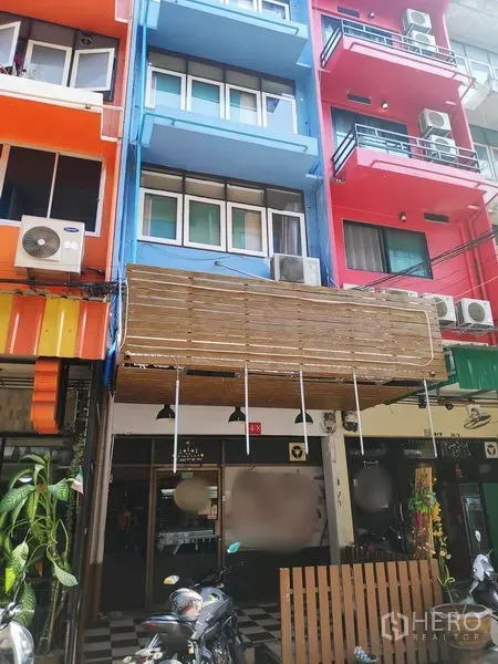 Townhouse for rent in Sathon, Bangkok - Colorful shophouse row with a blue multi‑storey townhouse, balconies, awning and streetfront AC units.