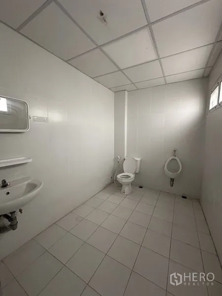 办公空间 出租在Khlong Toei, Bangkok - 整洁的卫生间，白色瓷砖，配有坐便器、小便器、洗手盆和小窗。