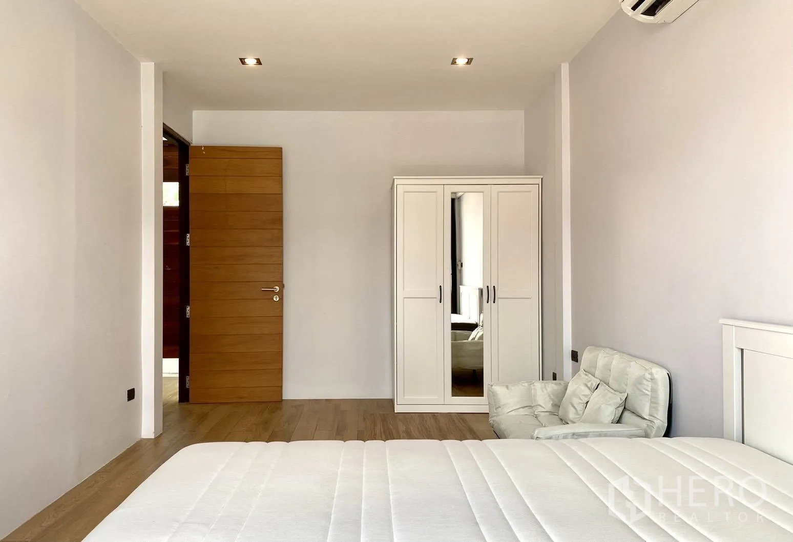 Townhouse for rent in Watthana, Bangkok - Bedroom featuring a white wardrobe, armchair and wooden door.