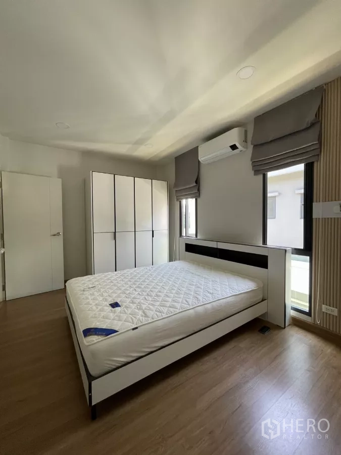 独立式住宅 出租在Bang Phli, Samut Prakan - 采光良好卧室，黑白床架、衣柜与空调。