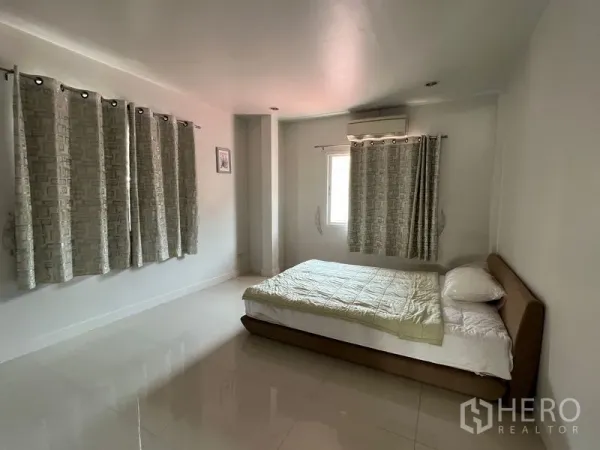 Detached House for rent in Bang Kapi, Bangkok - Spacious bedroom with double bed, tiled floor, curtains and air conditioning.