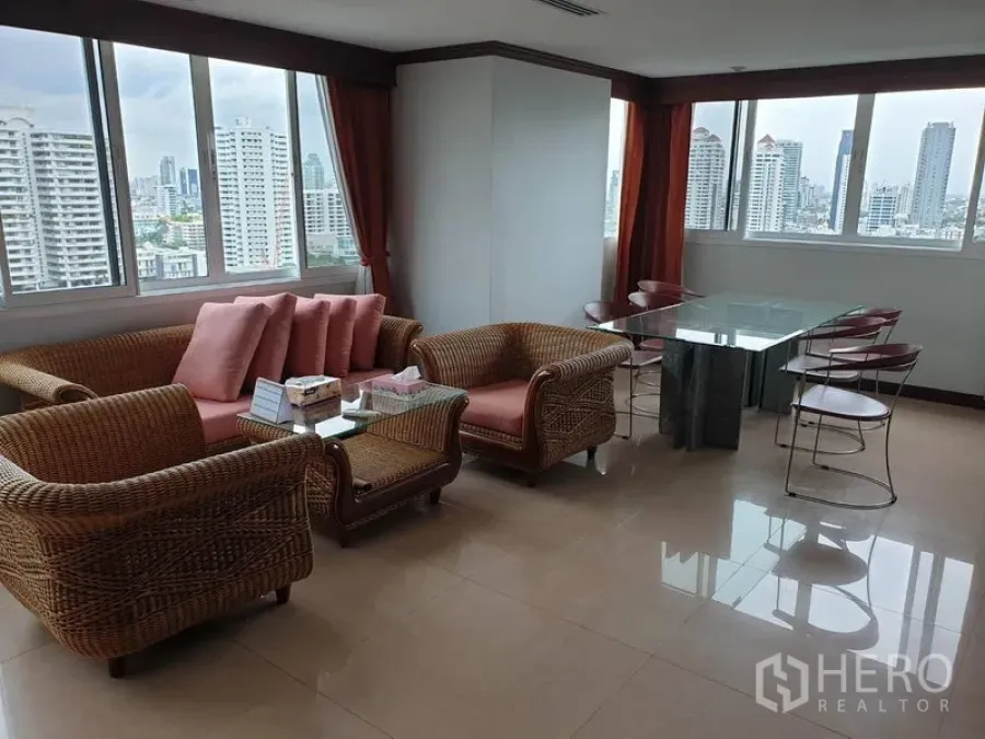 公寓 出租在Watthana, Bangkok - 明亮的客餐厅，藤编沙发、玻璃餐桌，大幅落地窗带来曼谷城市天际线景观。