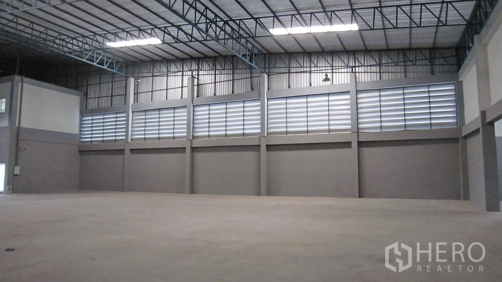 仓库 for rent in Bang Sao Thong, Samut Prakan - 仓库内墙体带通风百叶，高顶下开阔地面。