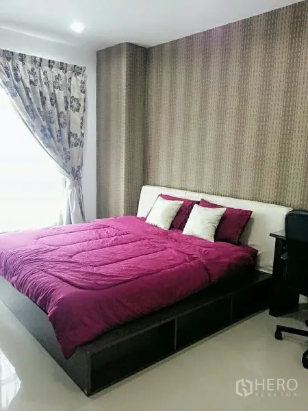 Condominium for rent in Khlong Toei, Bangkok - Bright bedroom with large bed, patterned curtains and a feature wall.